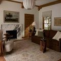 Milena Ivory / Granite Rug styled in a living room with brown sofa, armchair, and wooden accents