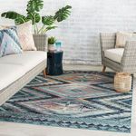 Rug styled in modern indoor space between two armchairs and a side table