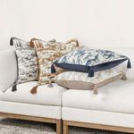 Four Stonework Throw Pillows in blue, tan, beige, and black toile designs arranged on white sectional sofa