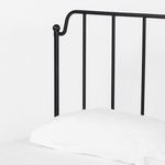 Top corner close-up showcasing rounded iron post and smooth vertical bar on the headboard with white bedding