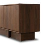 Side perspective highlighting clean lines, walnut grain, and structured plinth base