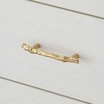 Close-up of gold twig-style drawer handle on sand white textured drawer front