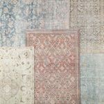 Multiple vintage-inspired rugs layered, including the Bardia rug in dark teal and rust