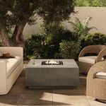 Donovan Outdoor Fire Table styled in an outdoor patio with ivory sofa and natural wicker chairs