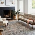 Rug styled in living room under sofa and armchair with fireplace and natural light through windows