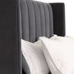 Close-up of winged headboard corner with two white pillows resting against it