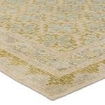 Detailed view of hand-knotted texture at rug corner highlighting fiber and muted blue-green hues
