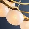Angle showing multiple seedy glass shades and gold metal chains with curved metal bands