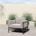 Hearst Outdoor Chair on smooth concrete floor near green potted plants and tall light-colored textured wall