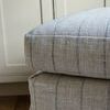 Close-up of ottoman’s cushioned top corner with visible striped fabric texture and stitching detail