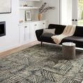 Rug styled in a living room with black couch, white walls, and a small gray side table