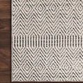 Corner of rug placed on dark hardwood floor showing detailed geometric pattern and pile contrast