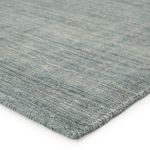 Close-up of rug corner showing fine weave texture and tightly bound edges in blue and gray tones