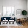 Modern living room with blue couch and tan chairs featuring the Trula black tripod end table