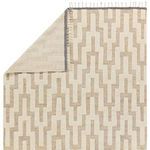 Corner folded to reveal reverse side of rug with muted cream and tan chevron pattern