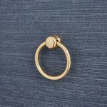 Close-up of the warm gold round metal ring pull on navy blue textured drawer front.