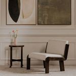 Interior scene showing chair angled with side table, floor lamp, and two framed artworks