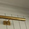 Close-up side angle of brass picture light mounted on white vertical planks