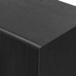 Close-up corner angle of console showing black oak finish and detailed joinery on edges