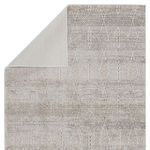 Back corner of rug folded to show solid cream backing and front trellis design