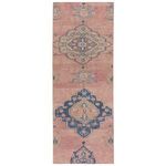 Southwestern style rectangular runner rug with pink background and blue, tan floral medallion patterns