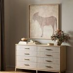 Burro Marron painting displayed above light wood dresser styled with pottery and plants in minimalist room