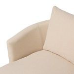 Close-up showing corner of armrest and loose beige pillow on chaise