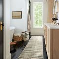 Humphrey Natural / Moss Rug in a narrow bathroom runner style on black tile flooring