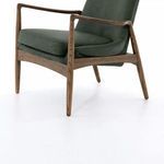 Close-up revealing wood grain on armrest next to plush green leather cushion