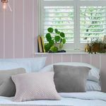 Bedroom setting showing wallpaper applied behind bed with white shutters and decorative pillows