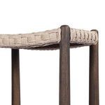 Close-up view underneath seat displaying woven rope pattern and dark wood rounded legs