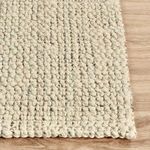 Angled corner view highlighting rug edges and dense loops of jute fibers on hard floor