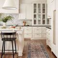 Narrow Jules rug runner placed in a white kitchen with dark chair and wood flooring