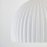 Detailed view of fluted white glass surface texture on bottom edge of pendant light shade