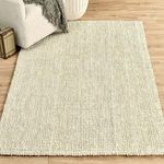 Rug styled in room setting with light wood floor, cream sofa, and decorative throw