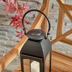 Top angled view of Antoinne Outdoor Lantern showing handle curve on wooden chair with stone wall