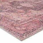 Traditional low-pile area rug with softly faded pink, dark purple, and tan tribal medallion and floral pattern