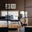 View through black door frames showing bed with patterned pillows and light wood nightstand