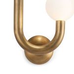 Close-up on lower brass U shape and round wall mount with warm brushed texture and patina finish