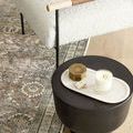 Close-up detail of Layla rug pattern near black side table and textured white armchair legs