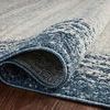 Side view of folded rug edge rolled on a dark wood floor highlighting thickness and weave detail
