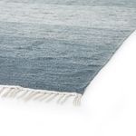 Close-up of navy ombre rug corner showing white fringe and flat woven texture