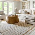 Brett lumbar pillow styled on white armchair in bright living room with beige sofa and rattan coffee table