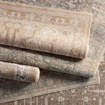 Stacked rolled rugs showing various neutral color variations and traditional medallion patterns