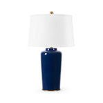 Table lamp with a glazed ceramic midnight blue base and a white drum shade topped with a brass finial