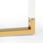 Close-up of polished brass iron corner joint where clear acrylic leg meets base