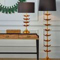 Decorative box displayed on desk beside gold table lamp and tall floor lamp in room with panel walls