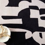 Detail of cream and black abstract shapes partially covered by decorative bowl with coral