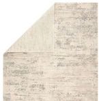Corner of Paxton Abstract Gray/Ivory rug flipped to reveal a solid ivory backing