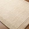 Close-up angled view highlighting the rug’s woven texture and natural cream-beige tones on wood floor